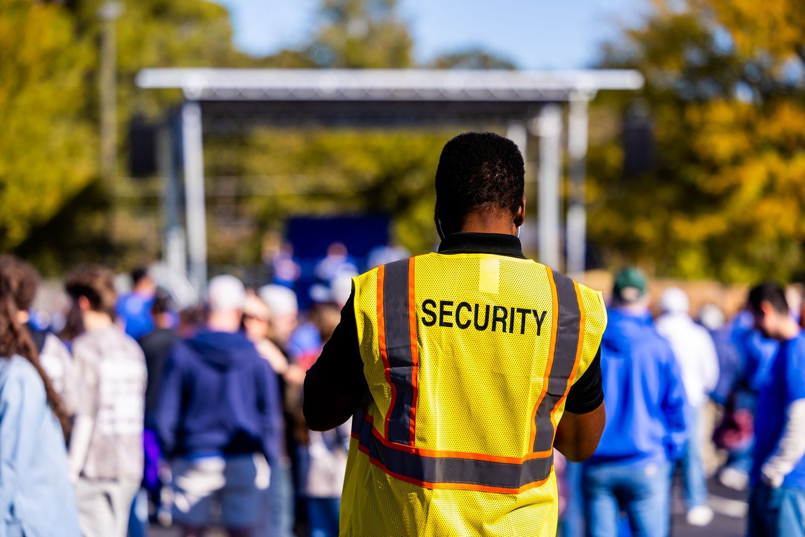 Event security officer in high-visibility SECURITY vest facing a crowd