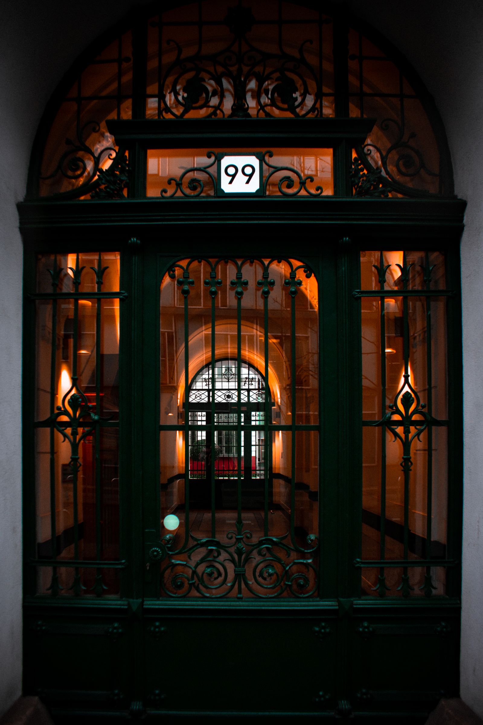 Ornate residential iron security gate with intercom at night